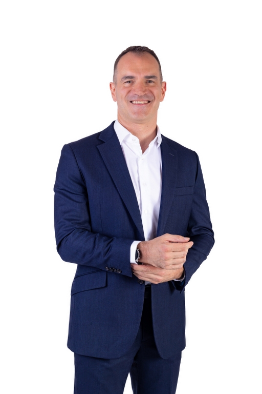 Professional corporate headshot of Vittorio Furlan, Independent Non-Executive Director, smiling confidently in a tailored dark blue suit against a clean white studio background